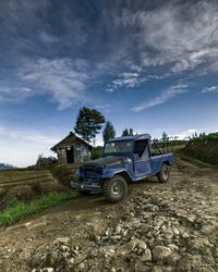 Car parked on road by agricultural field against sky