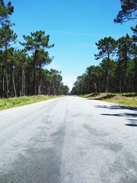 Empty road along trees and against sky