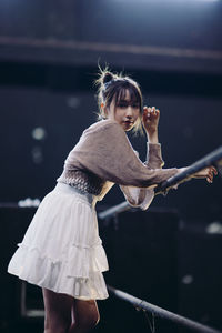 Rear view of young woman standing on railing