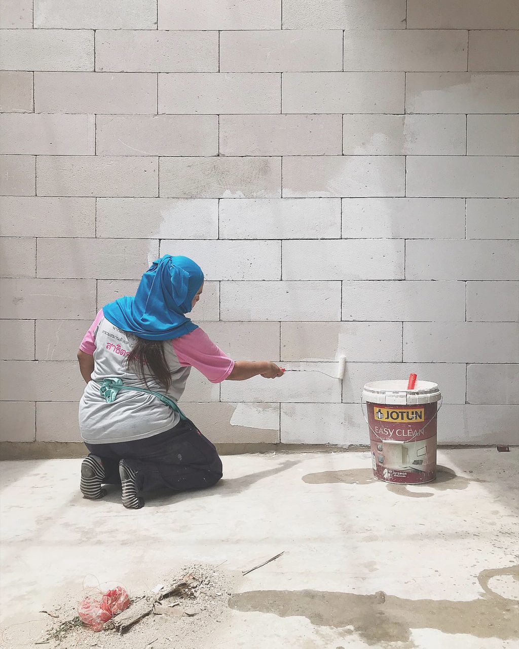 REAR VIEW OF WOMAN SITTING AGAINST WALL