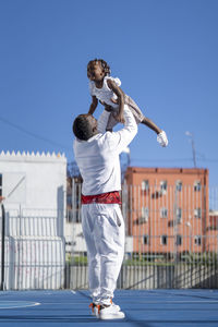 Father lifting daughter on sports court