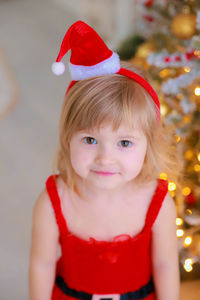 Portrait of cute girl standing against christmas tree