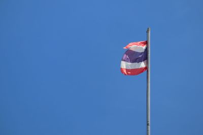 Low angle view of flags against clear blue sky