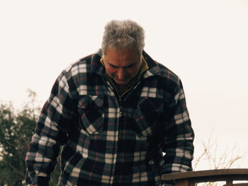 Man looking down against clear sky