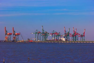 Cranes at commercial dock against blue sky