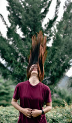 Rear view of woman standing against trees