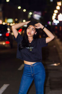 Portrait of beautiful young woman standing in city at night