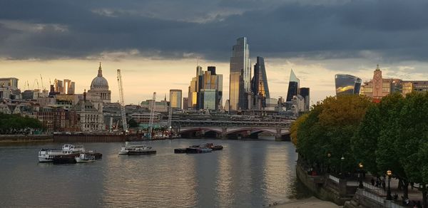 View of buildings at waterfront against cloudy sky