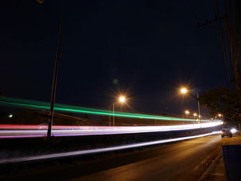 Light trails on road against clear sky at night