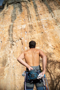 Rear view of shirtless man standing against rock formation