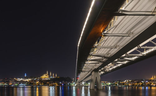 Illuminated bridge over river at night