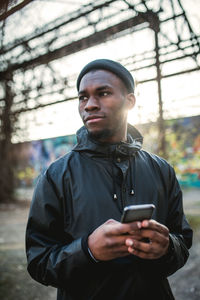 Man holding mobile phone while standing outdoors