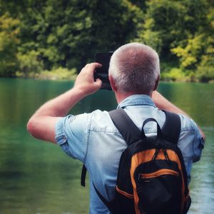 Rear view of man photographing lake