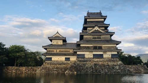 View of building by lake against sky