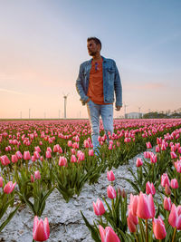 Woman standing on field by flowering plants against sky