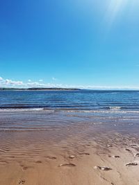 Scenic view of beach against blue sky