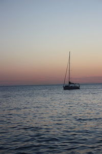 Sailboat sailing on sea against sky during sunset