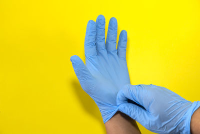 Close-up of human hand against yellow wall