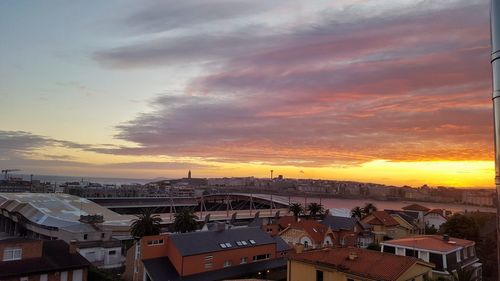 Aerial view of town by sea against sky during sunset