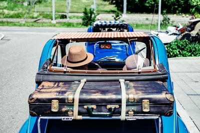 Rear view of friends with luggage sitting in vintage car