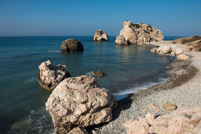 Rock formation in sea against clear blue sky