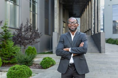 Portrait of young man standing against building