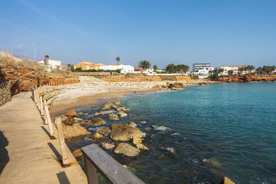 Scenic view of sea by buildings against clear sky