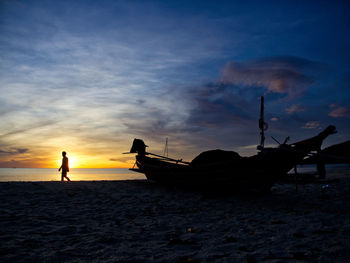 Silhouette people on beach against sky during sunset