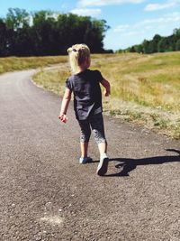 Rear view of woman walking on road