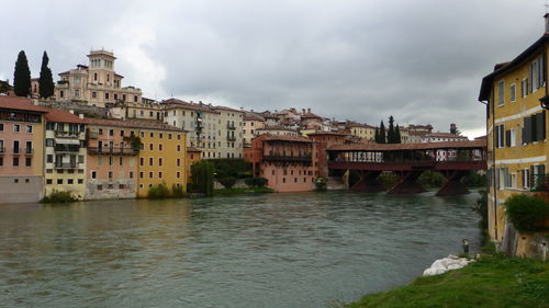 Buildings by river against sky in city