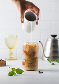 Cream is poured into cold black coffee with ice cubes. coldbrew. summer drinks.