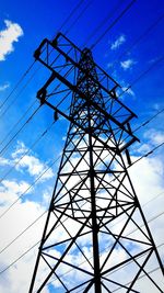 Low angle view of electricity pylon against blue sky