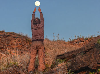 Rear view of man standing on field against sky