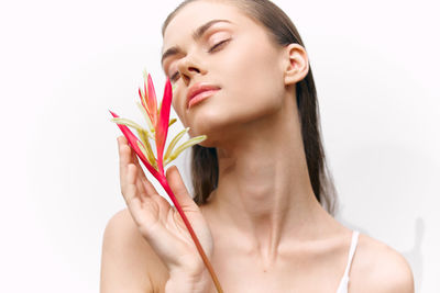Portrait of young woman holding plant against white background