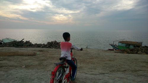 Rear view of boy on bicycle at beach