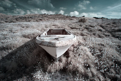 Abandoned boat on land against sky