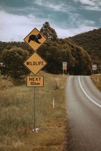 Information sign by road against sky