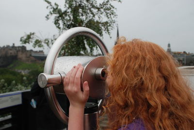 Close-up of girl looking through coin-operated binoculars