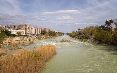 Scenic view of river against sky in city