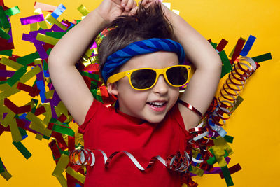 Child a boy in a red t shirt and sunglasses is lying on yellow paper resting at home