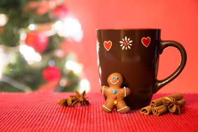 Close-up of gingerbread cookie and spices by cup on table