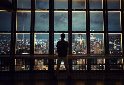 Silhouette man looking through window