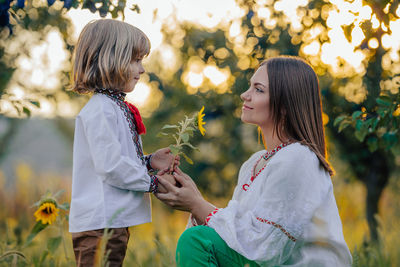 Side view of young woman holding flower