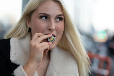 Close-up of smiling young woman looking away while eating food