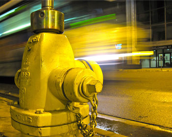 Close-up of yellow fire hydrant on road at night