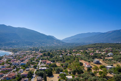 Aerial view of townscape and mountains against clear blue sky