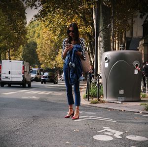 Woman with umbrella standing on road