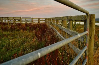 Fence on grassy field against sky