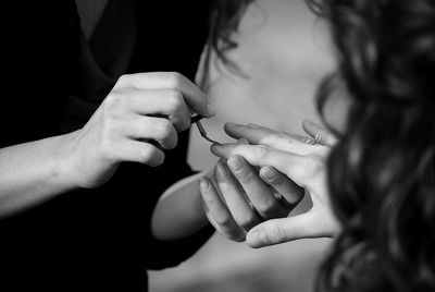 Midsection of woman applying nail polish to friend