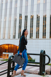 Young woman looking away against building in city